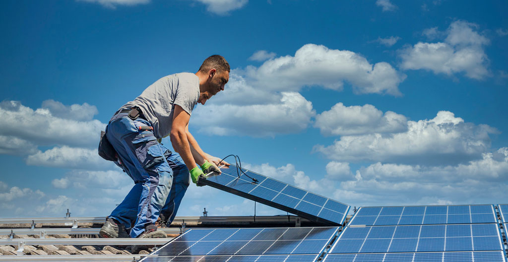 Technicien RGE inspectant une installation de panneaux solaires sur toiture résidentielle